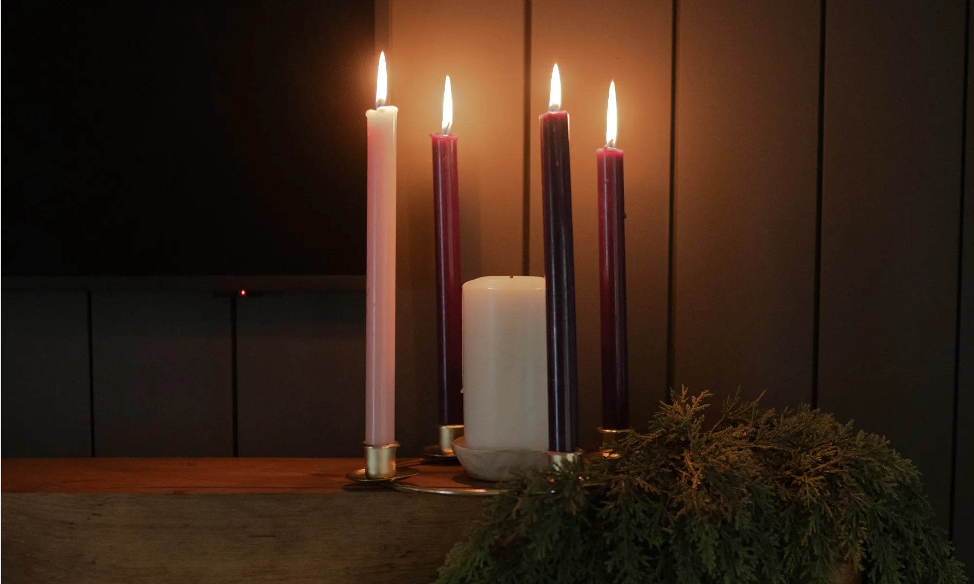 Candles lit next to a wooden wall