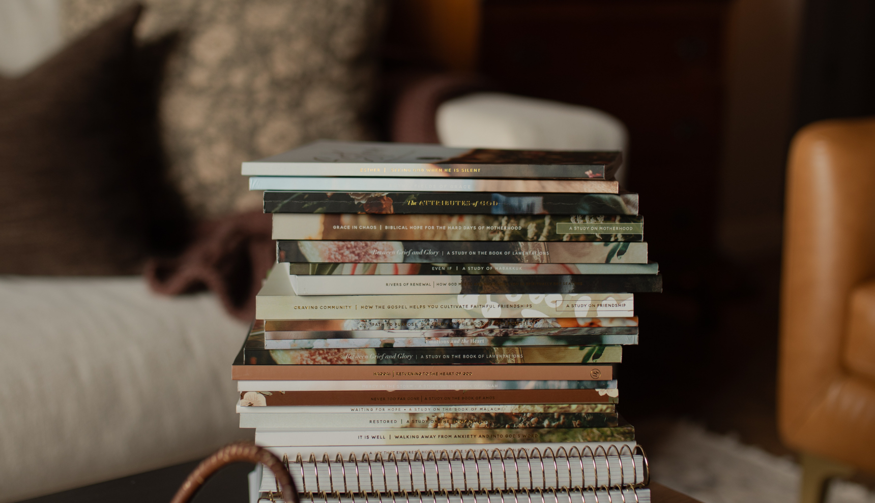 Multiple softcover studies stacked on multiple spiral studies on a wooden table