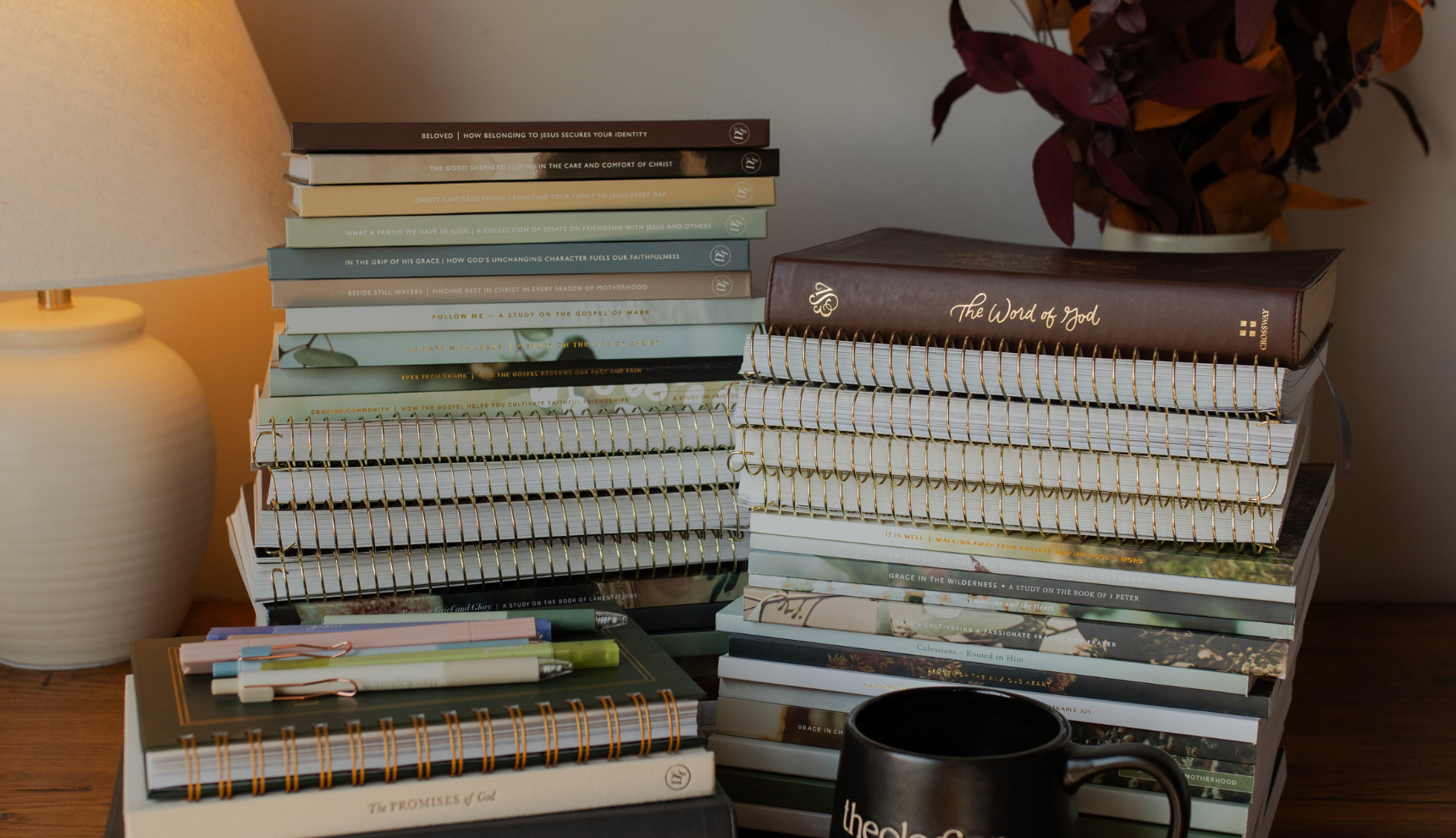 Multiple stacks of hardcover and spiral Daily Grace books next to a black mug that says theologian