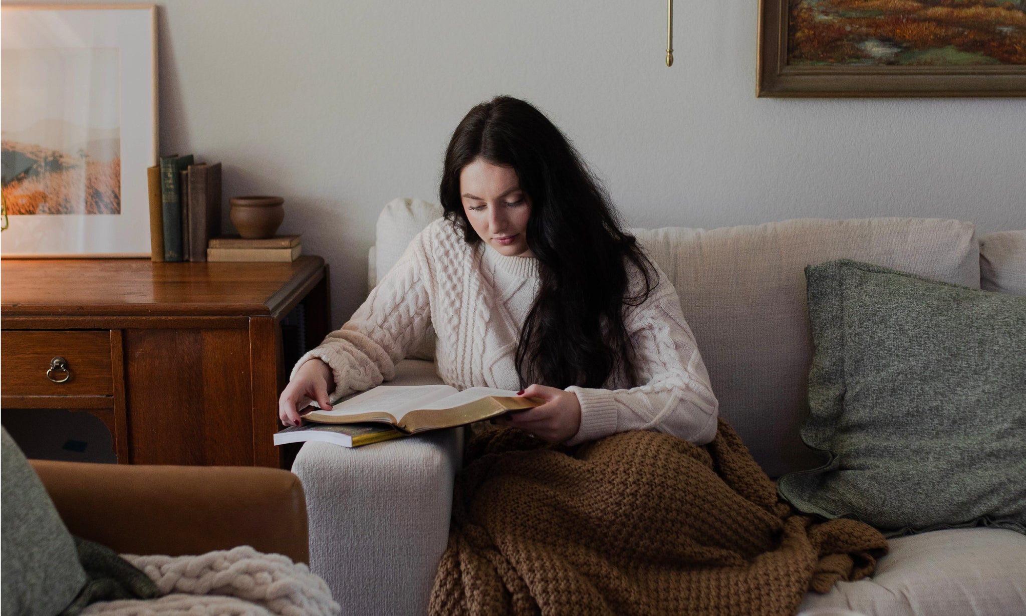 a woman sitting on the couch reading her Bible