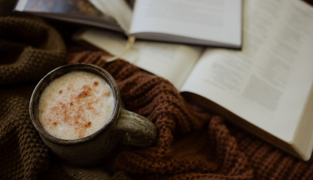 A cup of coffee on a woven blanket near an open blanket