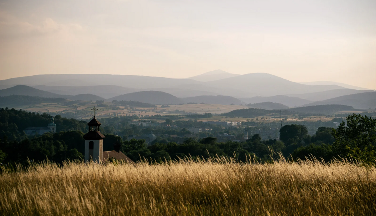 A hay field overlooking multiple churches and steeples in the far distance