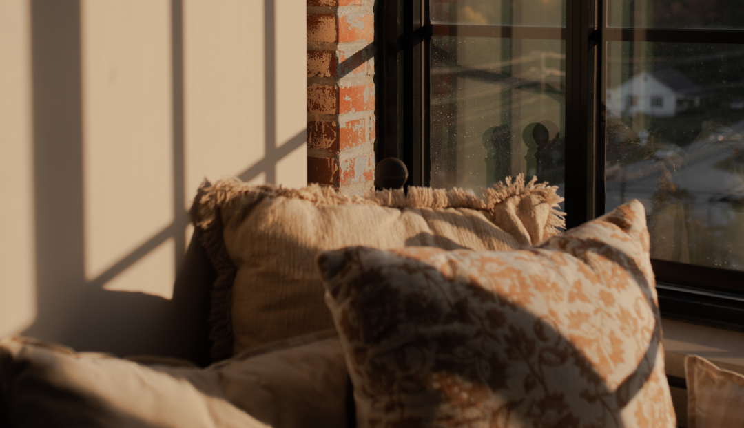 Two pillows near a windowsill and a wall