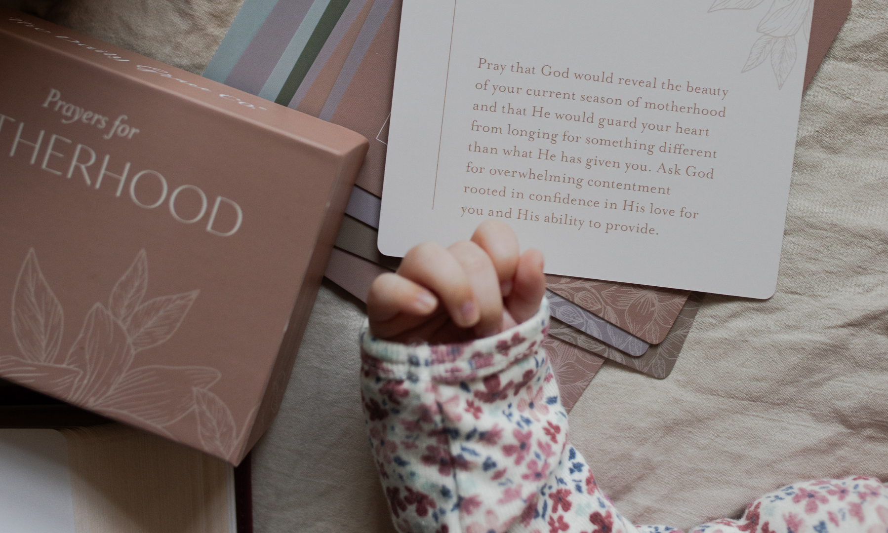 A child's hand near some prayers for Motherhood cards