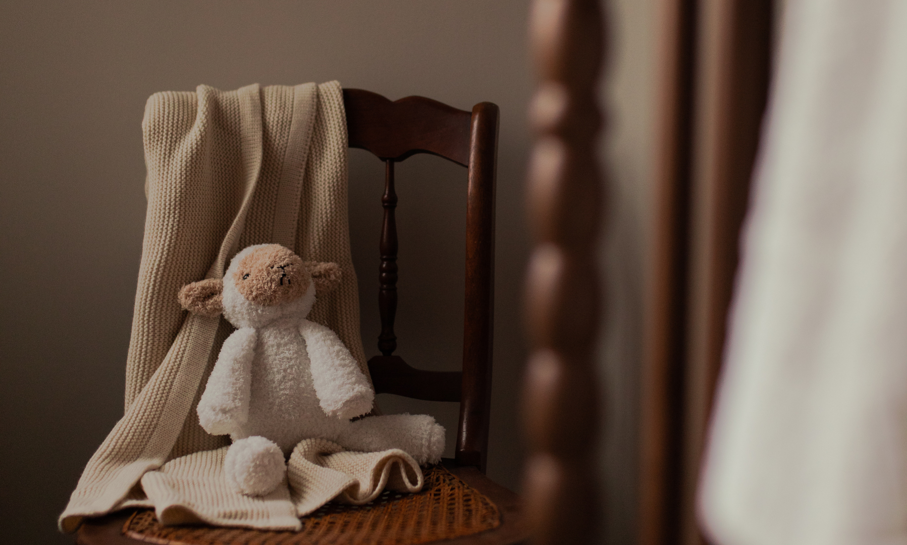 A stuffed animal lamb on a wooden chair