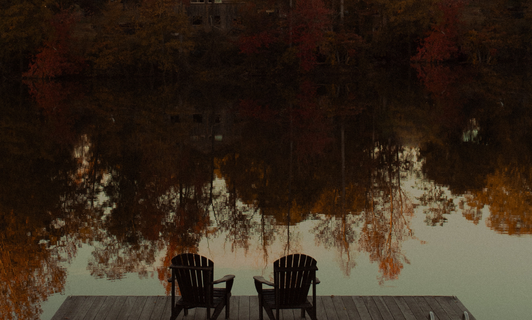Two chairs overlooking a lake and a reflection