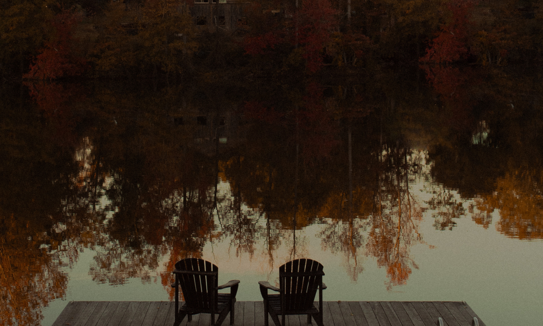 Two chairs overlooking a lake and a reflection