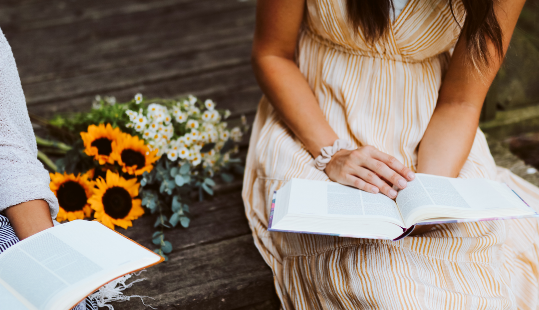 A woman reading a book with nearby flowers
