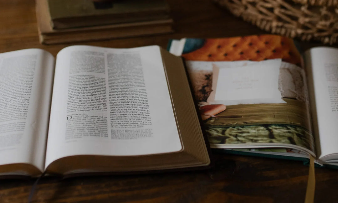 an open Daily Grace bible study next to an open bible on a brown wooden table next to a woven basket