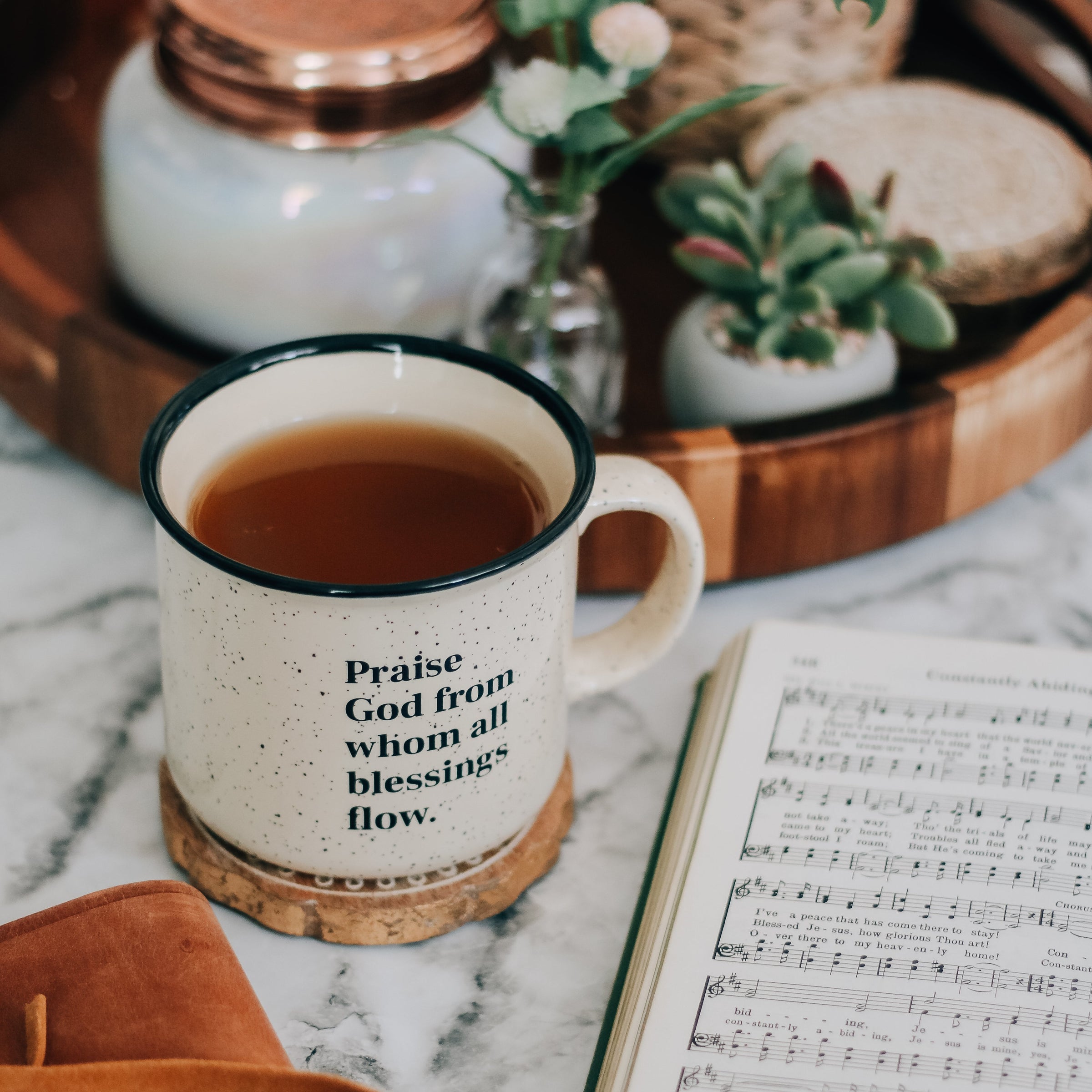 Doxology coffee mug next to hymnal