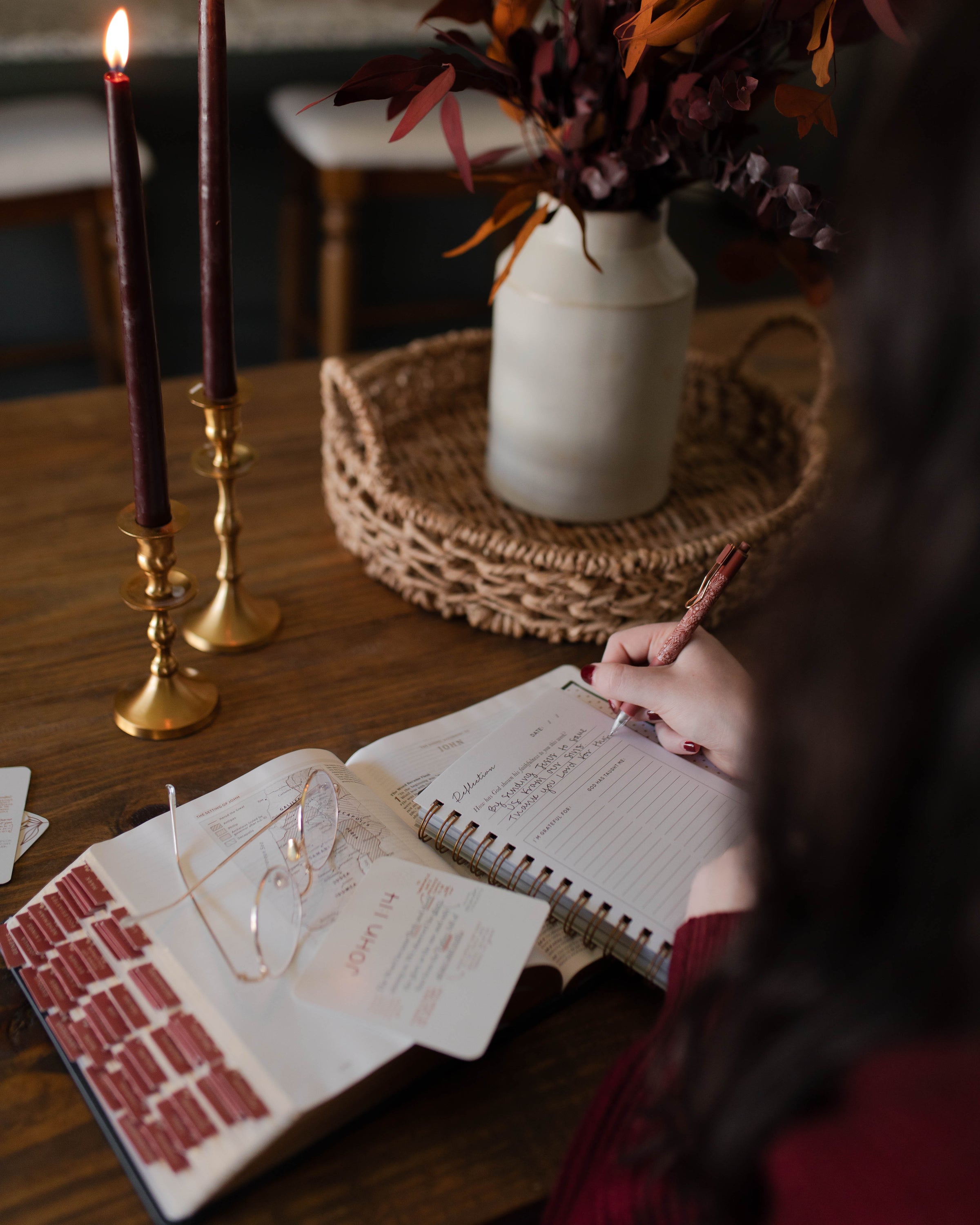 Woman writing in a journal next to a pair of glasses