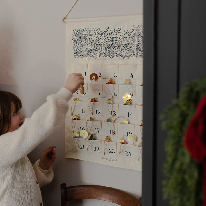 A girl putting a hanging decoration in a hanging calendar on the wall