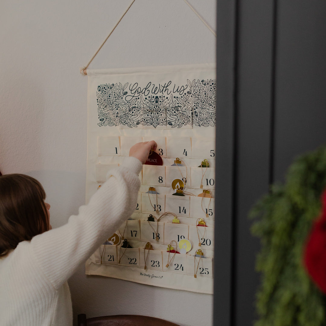 A child removing an ornament from the eight slot from a hanging advent calendar