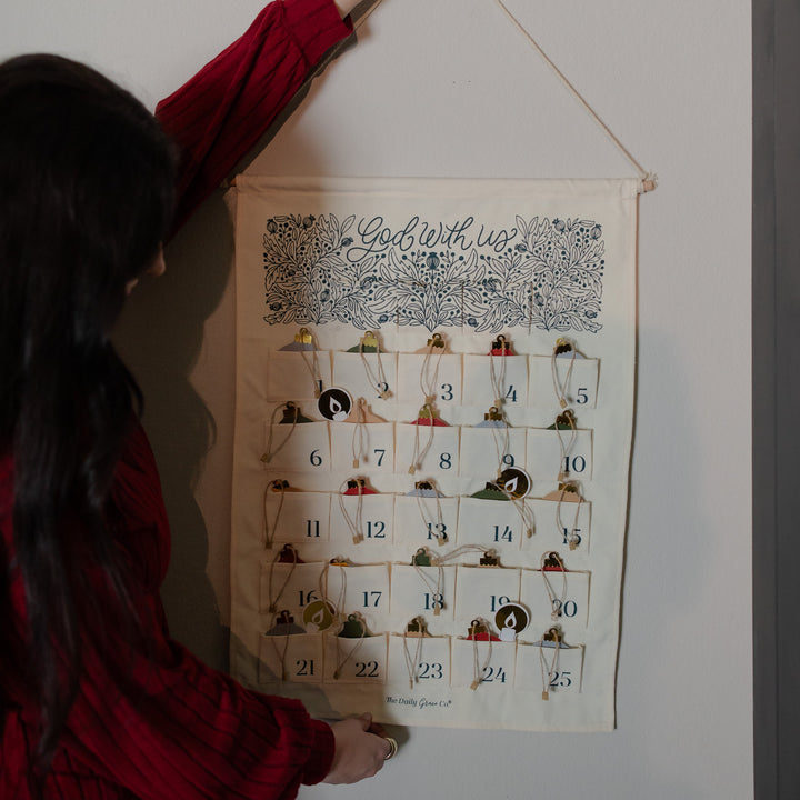 A woman hanging a Christmas advent calendar on a wall