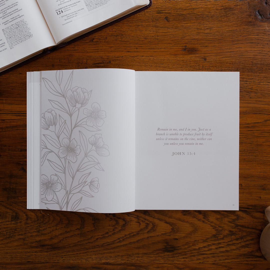 2026 Prayer Calendar opened to the devotional page on a wooden table next to an open bible