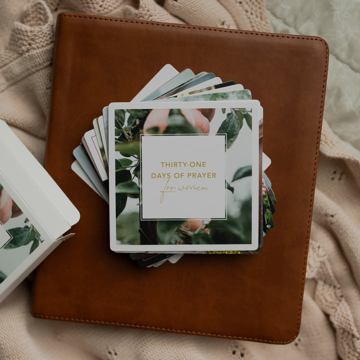 The 31 Days of Prayer cards stacked on a leather bible on a cream colored cloth