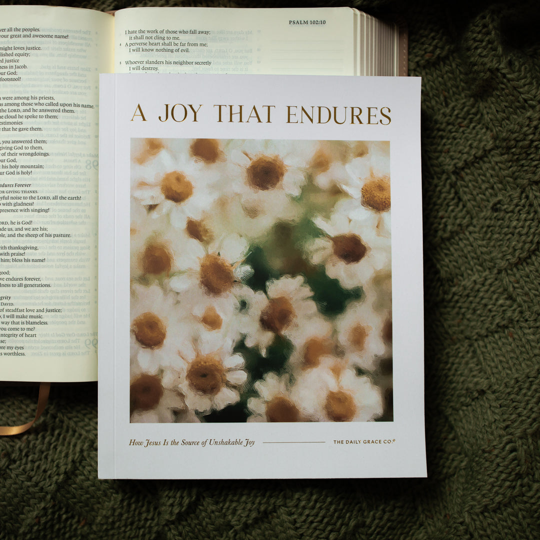 A Joy That Endures bible study cover laying on an open bible on a green knitted blanket