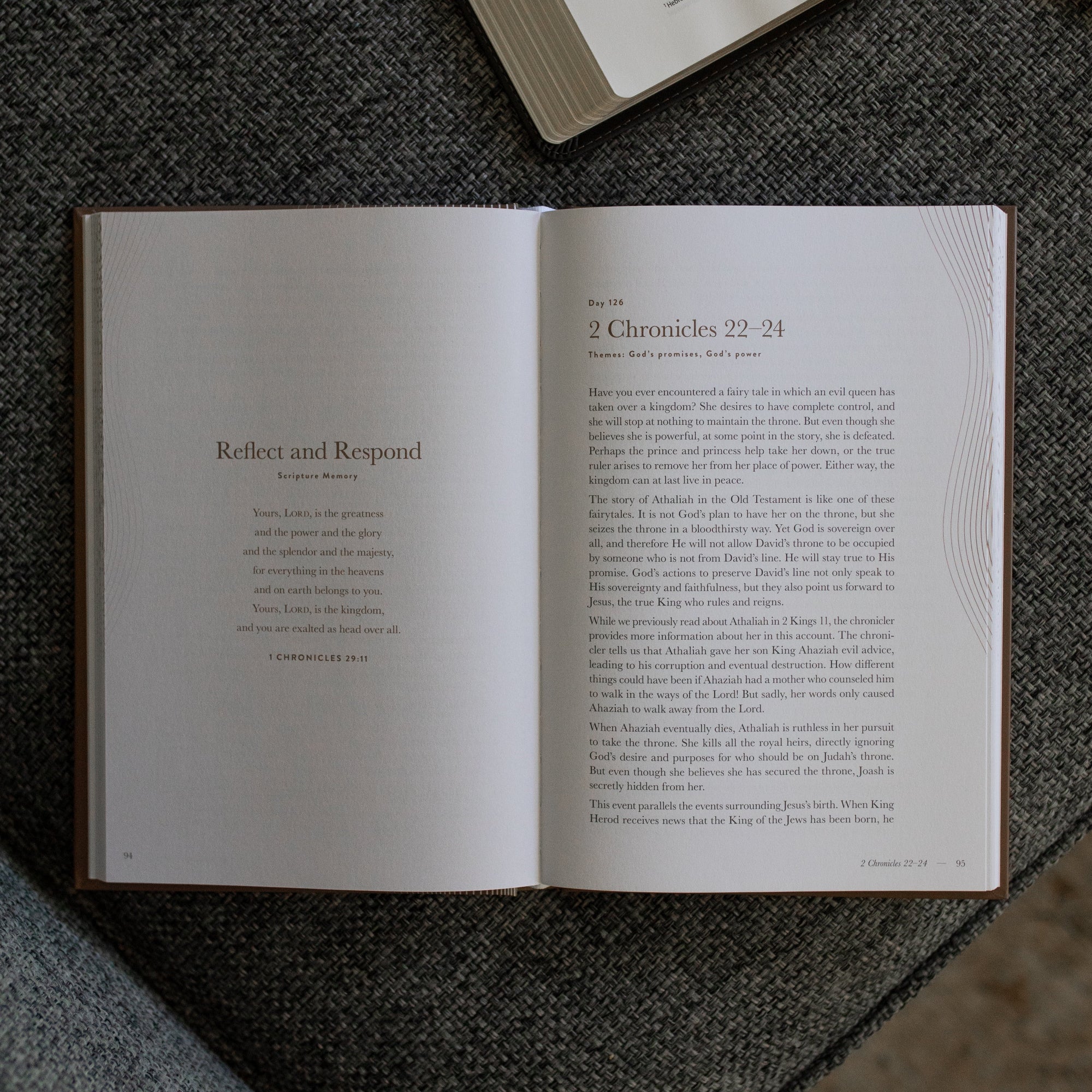 A Year in the Bible Mens Study opened to the Reflect and Respond page on a gray couch cushion