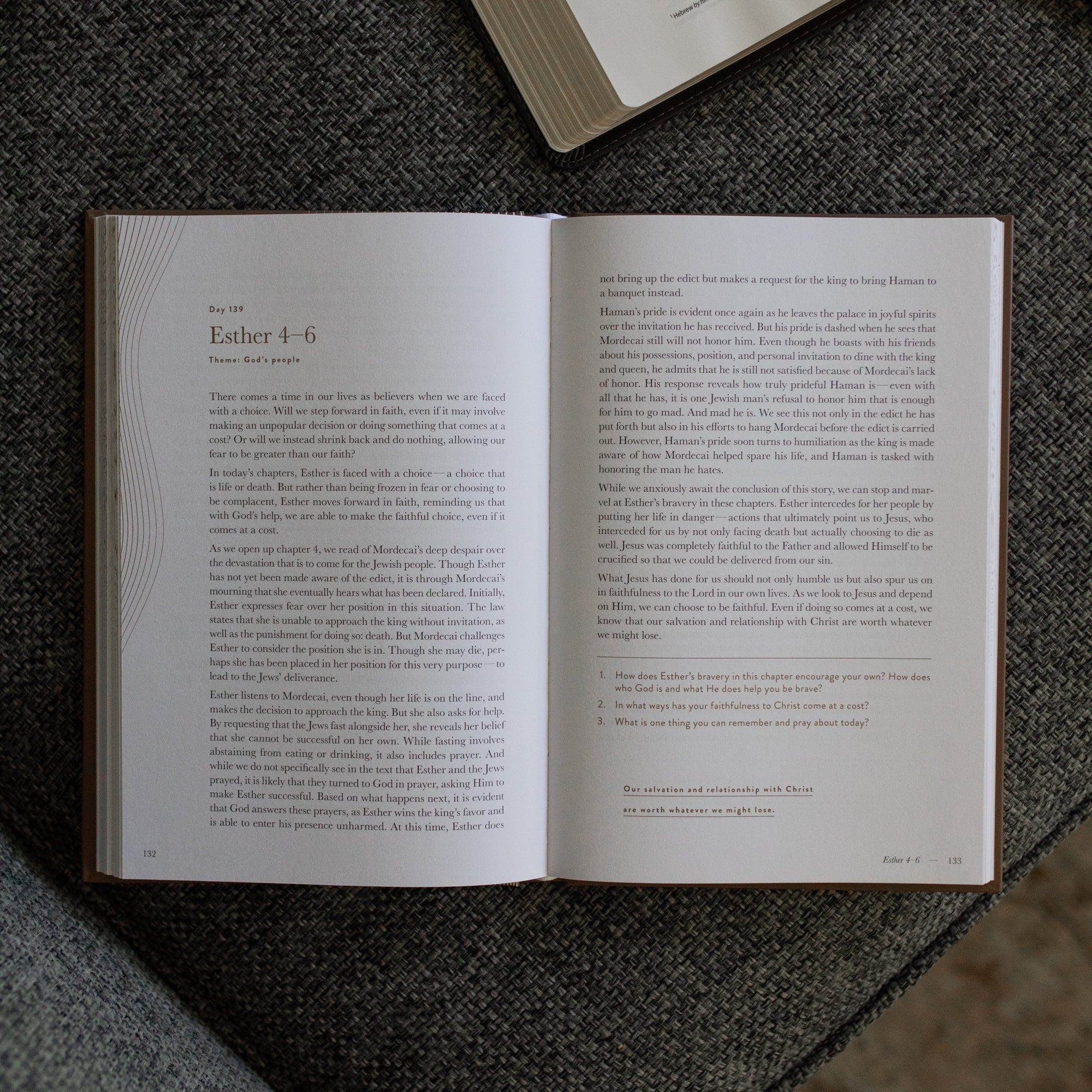 A Year in the Bible Mens Study opened to the Esther 4-6 page on a gray couch cushion