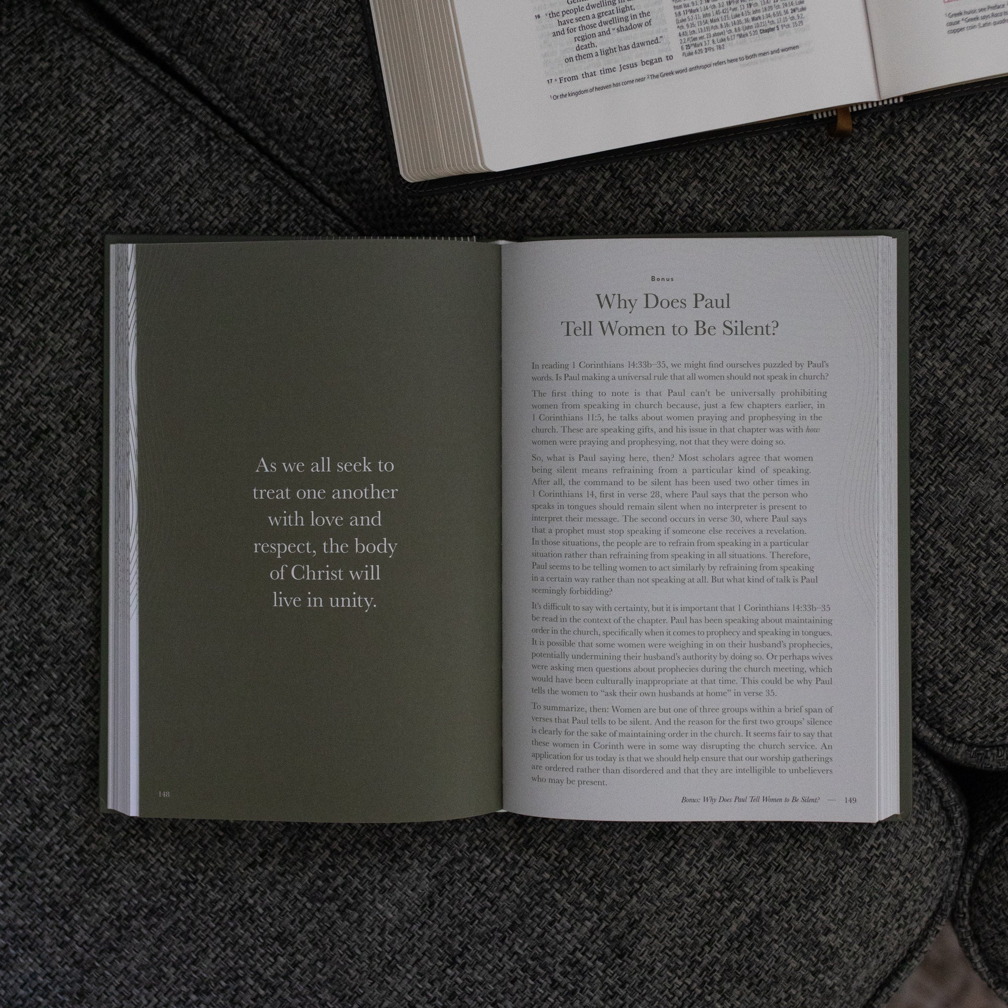 A Year in the Bible Vol 4 Hardcover opened to the Why does Paul tell Women to be silent reading page near an open bible on a grey couch cushion
