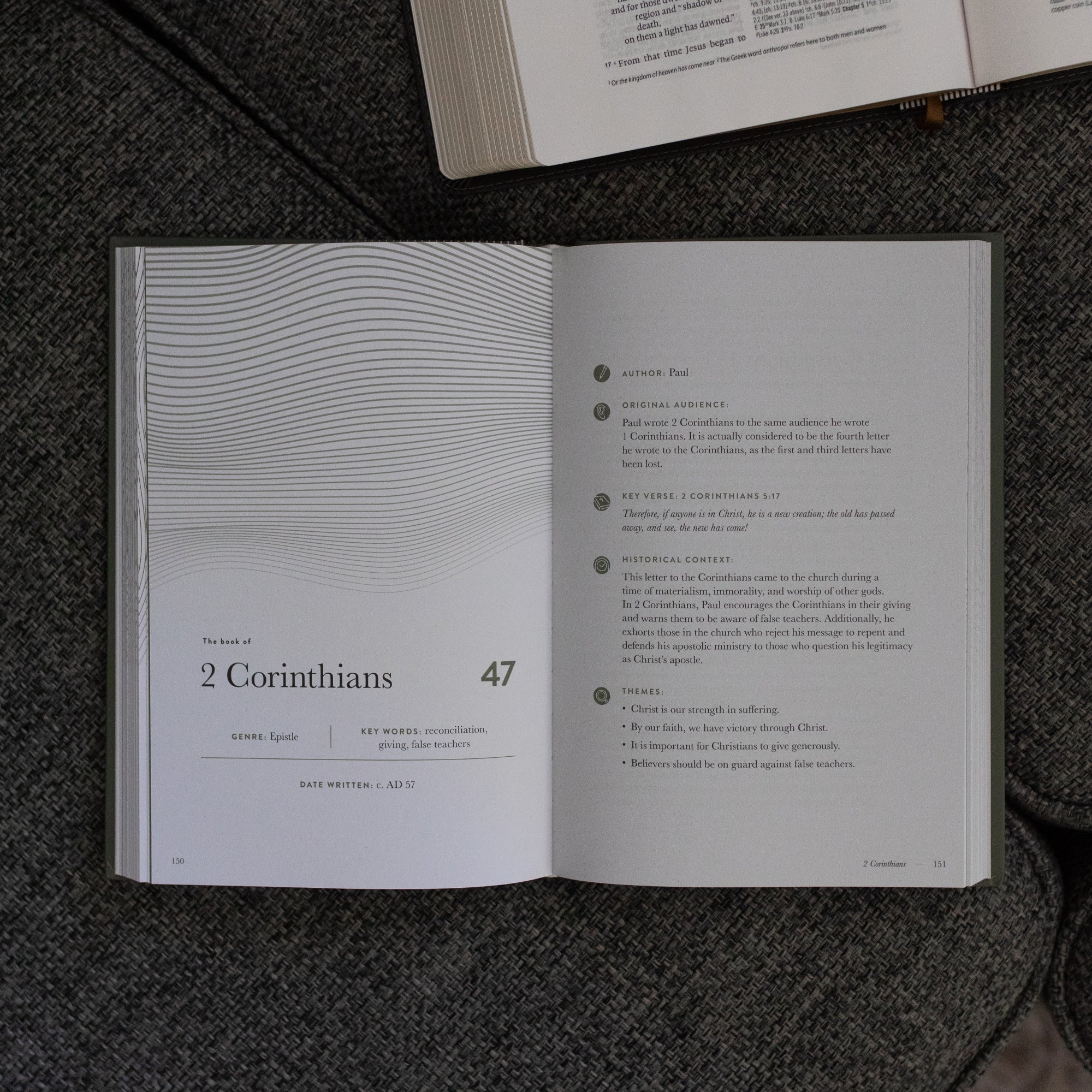 A Year in the Bible Vol 4 Hardcover opened to the 2nd Corinthians beginning page near an open bible on a grey couch cushion