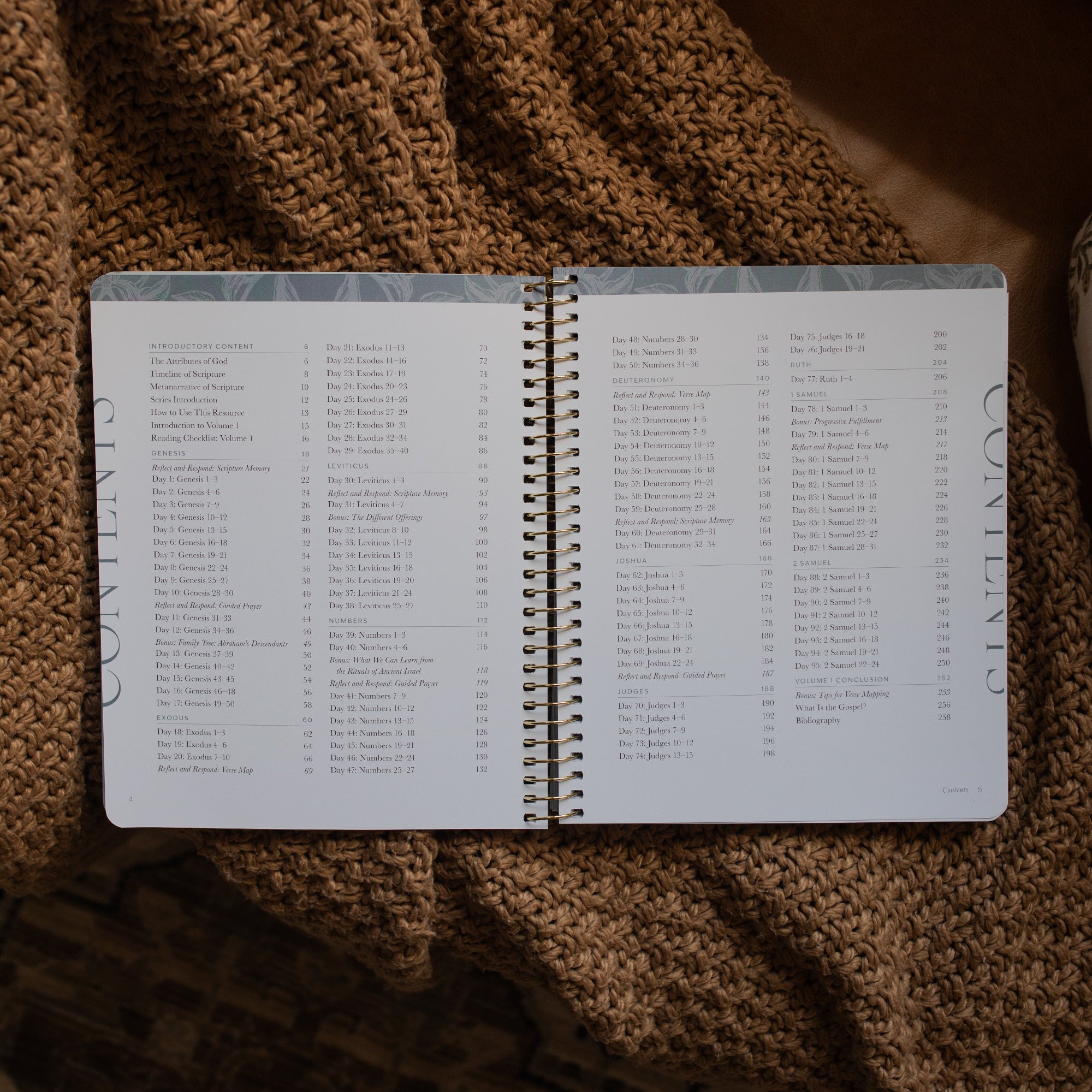 A Year in the Bible spiral opened to the table of contents page on a brown knitted blanket
