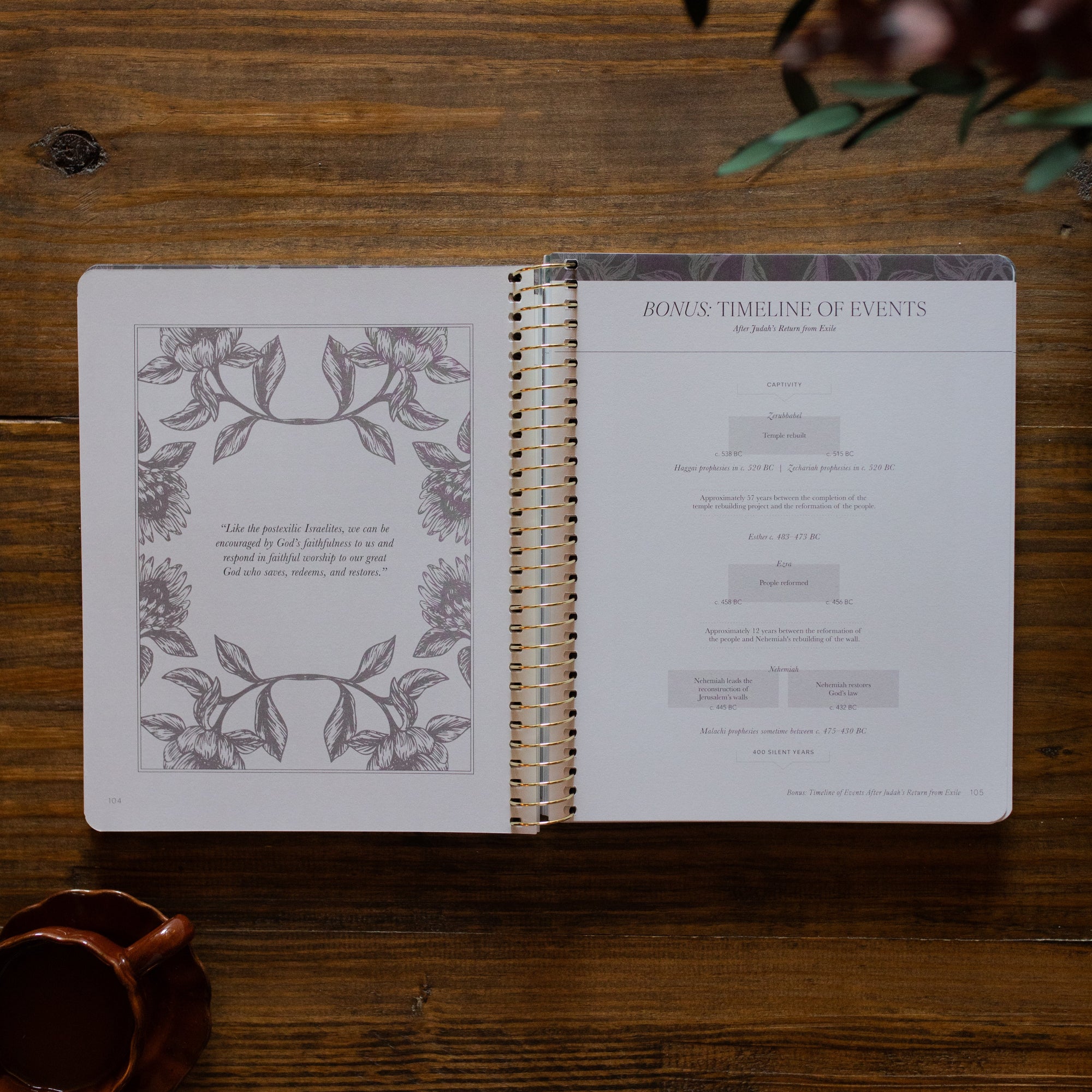 A Year in the Bible Spiral opened to the Timeline of Events page next to a brown coffee cup on a brown wooden table