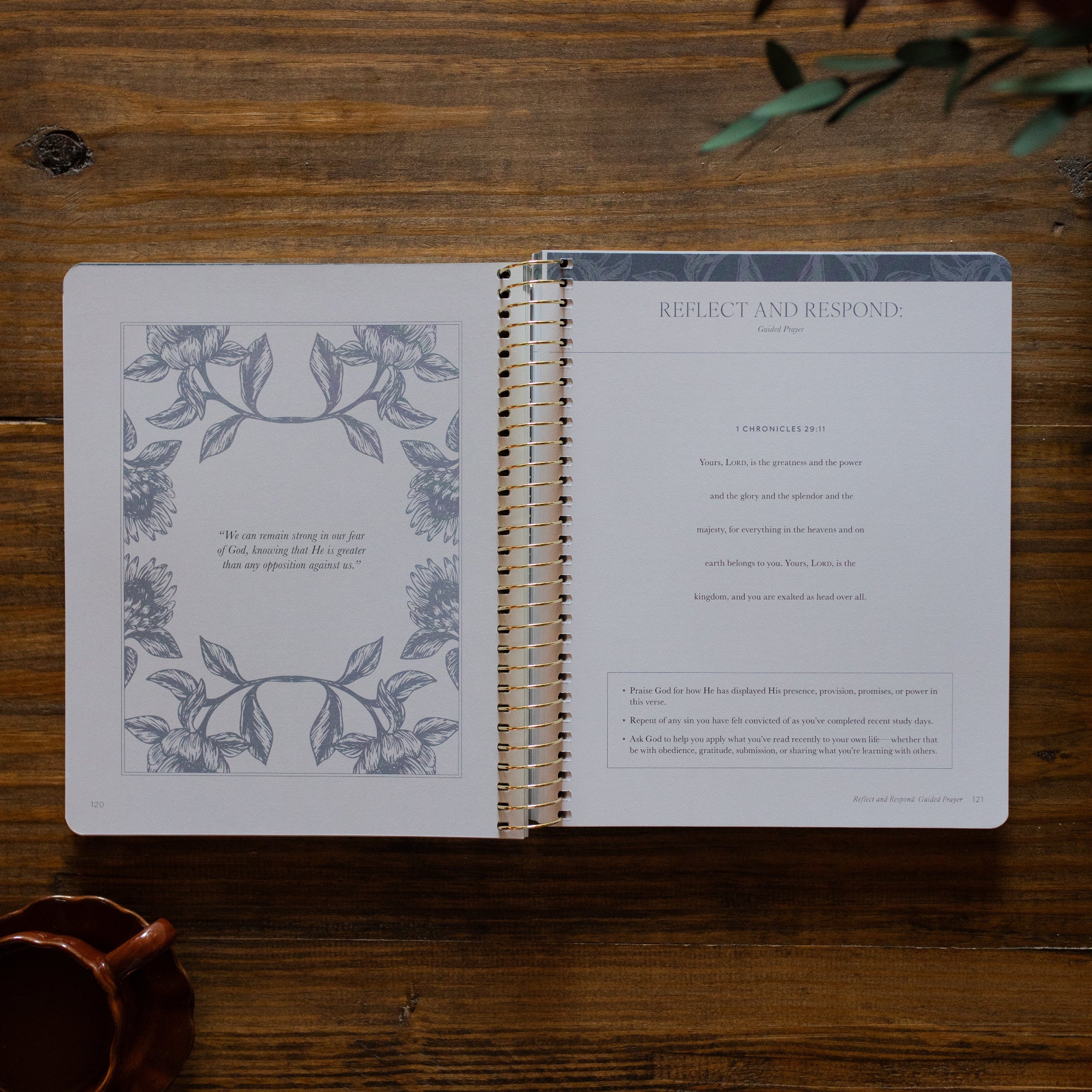 A Year in the Bible Spiral opened to the reflect and respond page next to a brown coffee cup on a brown wooden table