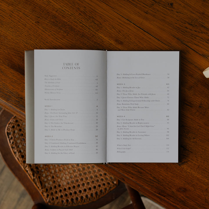 The Abide Hardcover opened to the table of contents page on a wooden table