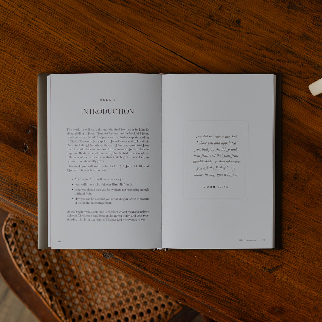 The Abide Hardcover opened to the Week 3 Introduction page on a wooden table
