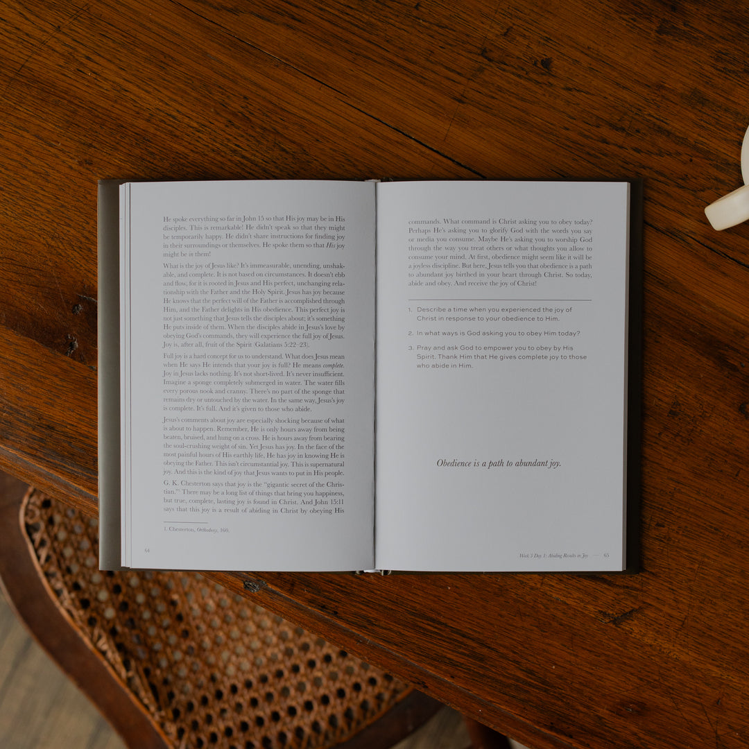 The Abide Hardcover opened to the Ending of Week 3 Day 1 Reading page on a wooden table