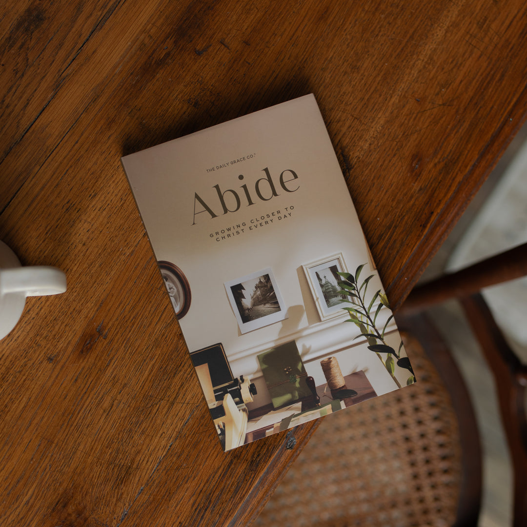 The Abide Hardcover Cover on a wooden table near a coffee cup