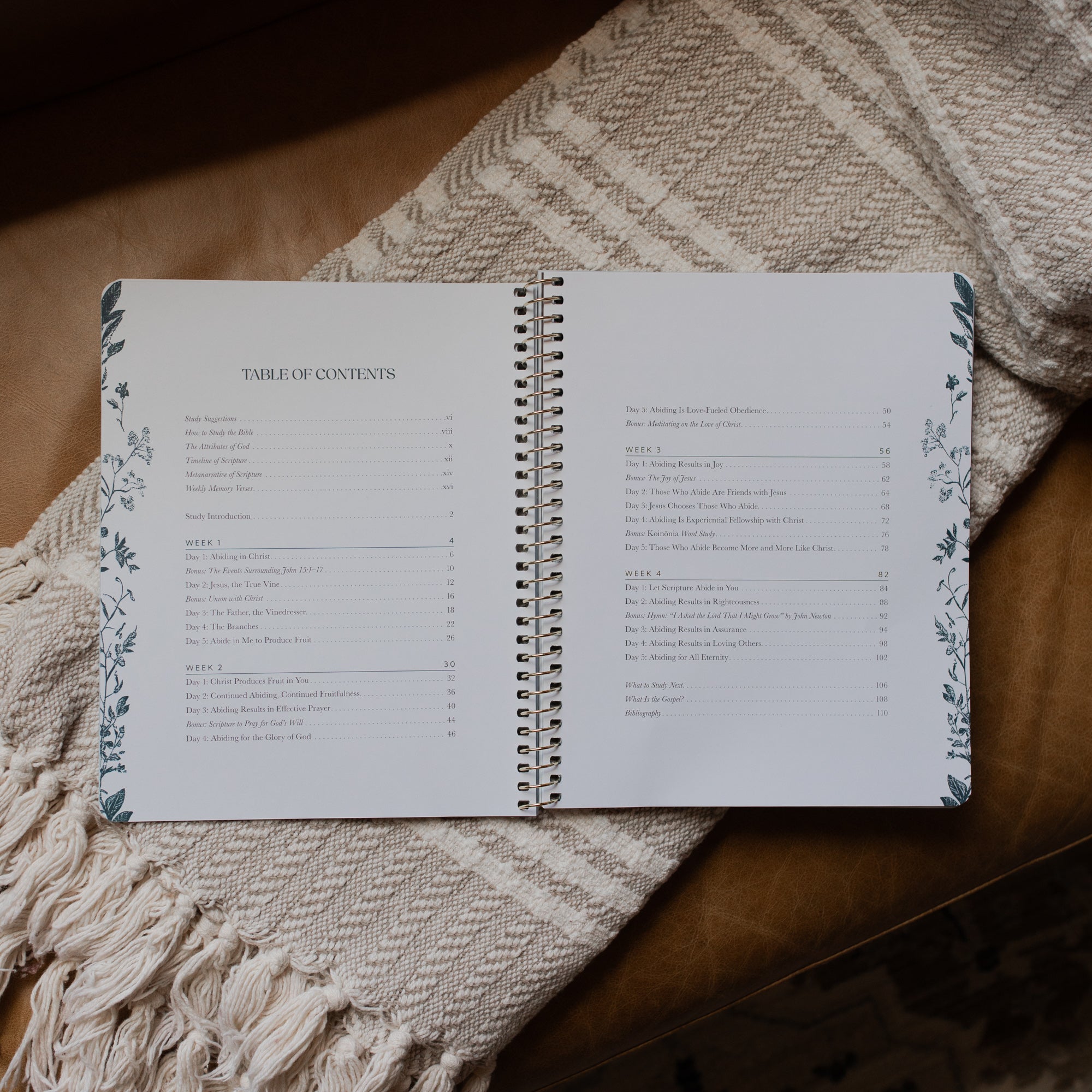 The Abide Spiral opened to the table of contents page on a cream colored blanket