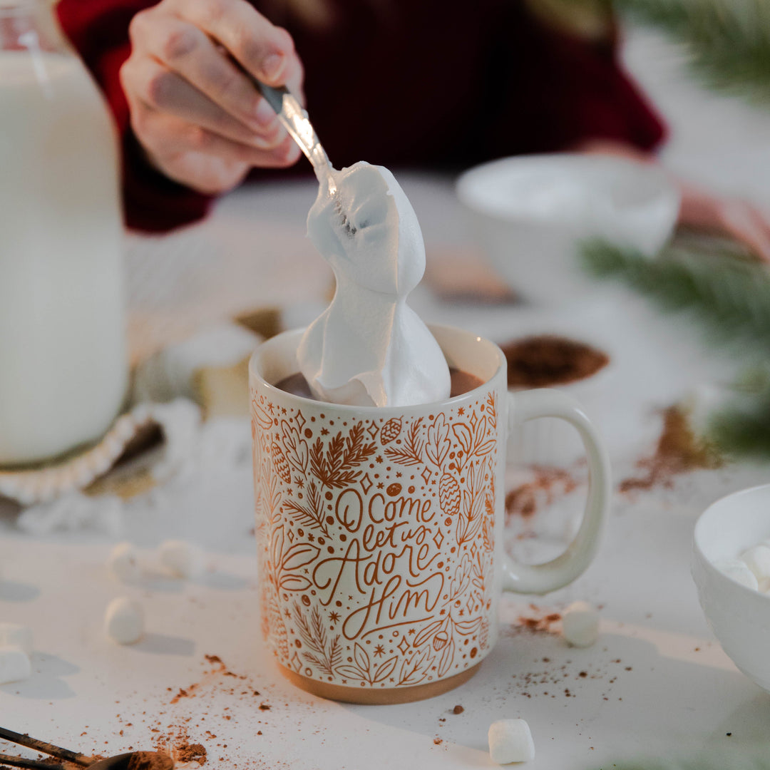 Whipped cream in Christmas mug that says O Come Let Us Adore Him for Christmas 