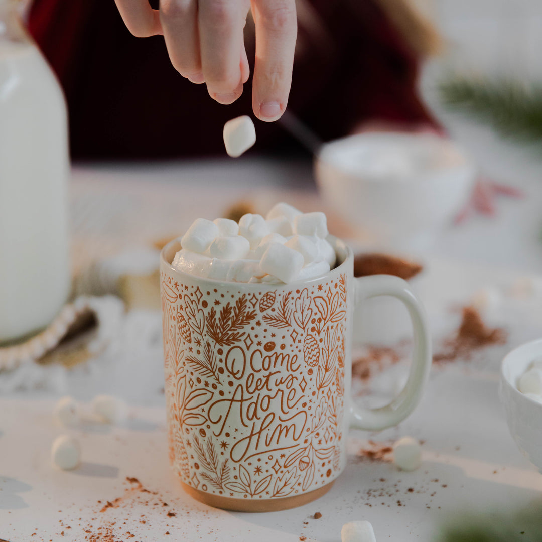 Christian woman putting marshmallows in Christmas mug 