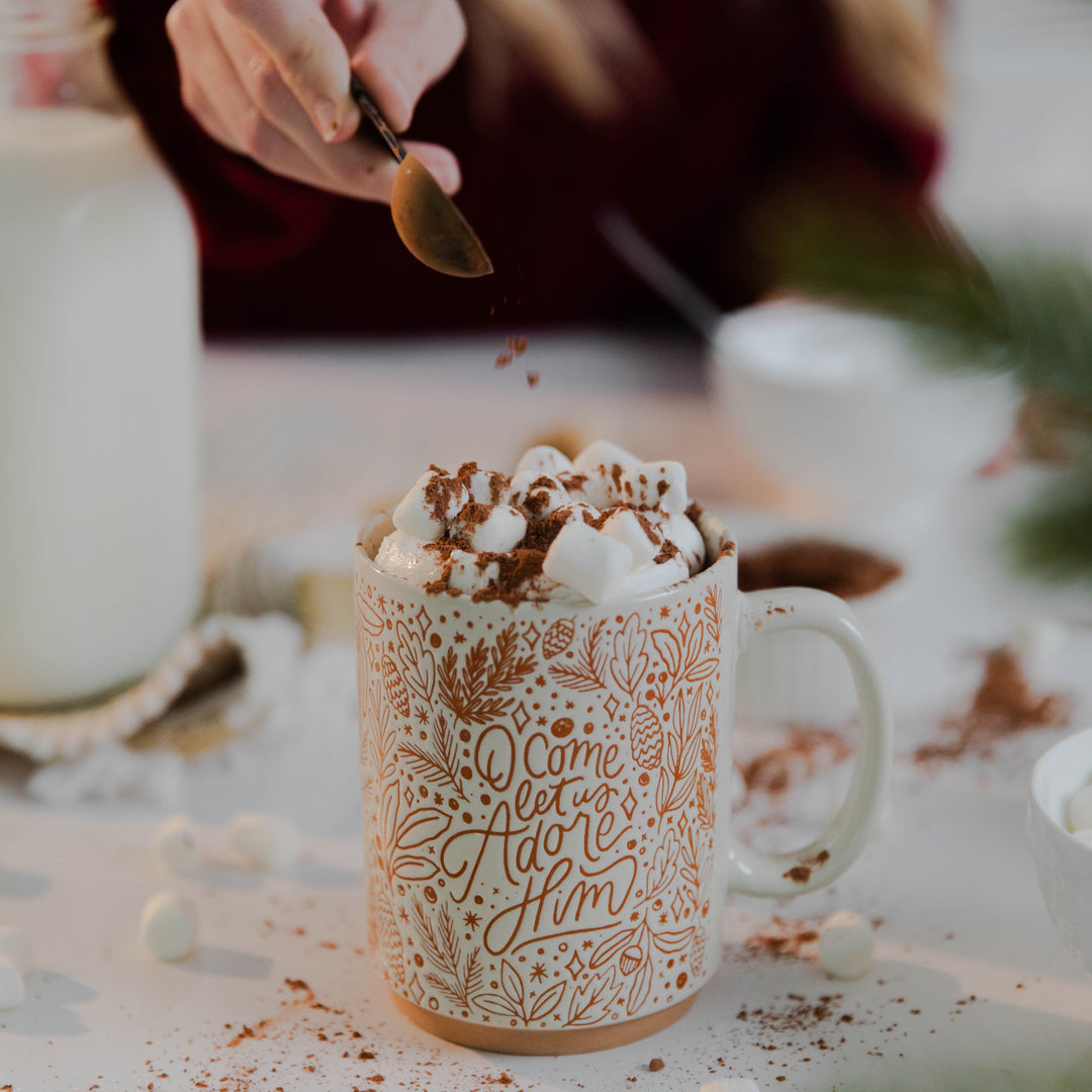 Woman pouring cinnamon on top of marshmallows for Christmas Advent mug