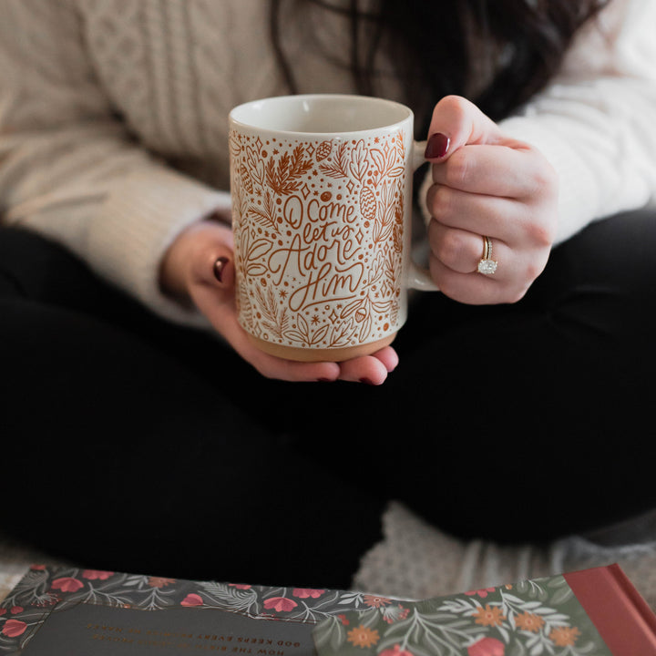 Woman holding Christmas mug that says O Come Let Us Adore Him