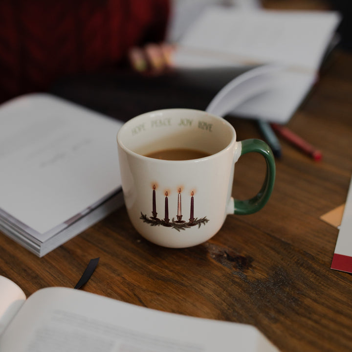 The Advent Adventure Mug on a wooden table next to an open Daily Grace study