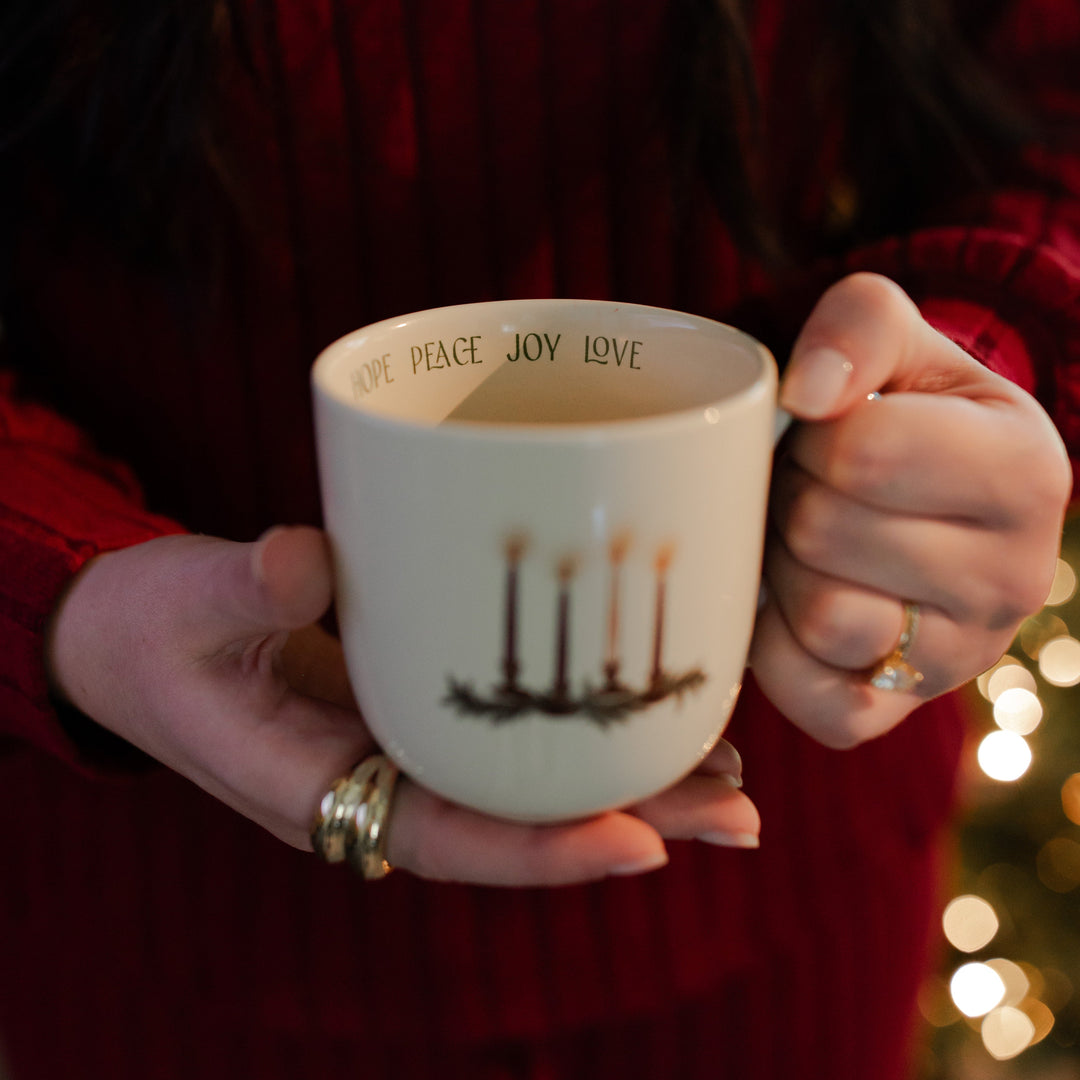 A woman holding the Advent Adventure Mug facing the camera up close