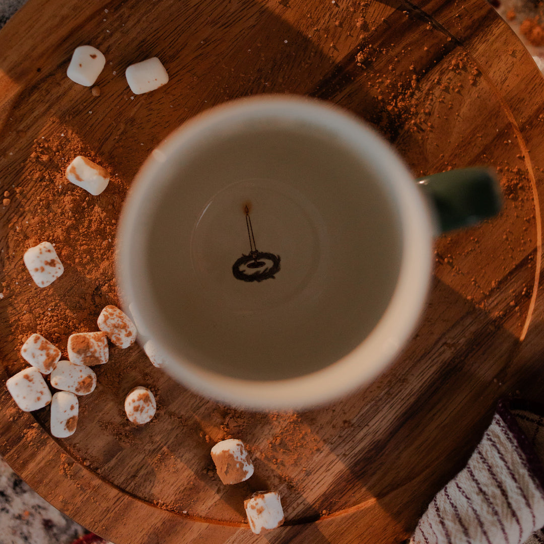 The inside of the Advent Adventure Mug sitting on a wooden table with multiple marshmallows sitting next to it