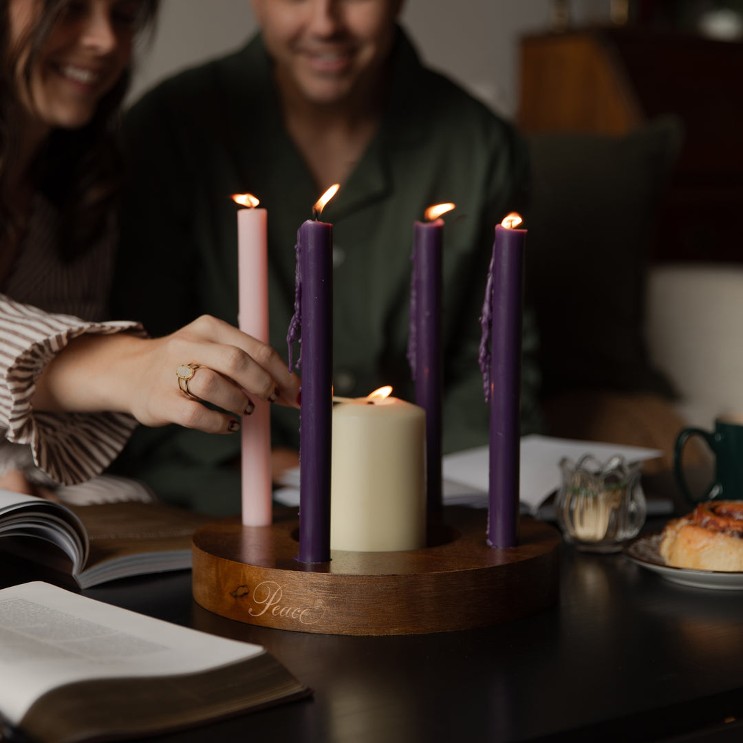 A woman lighting a candle on a dark wooden table