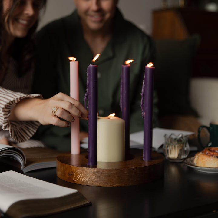 A woman lighting a candle on a dark wooden table