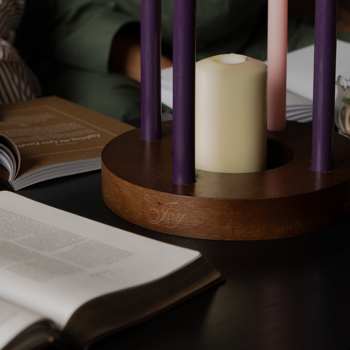 Up close to the side of a candle ring on a dark wooden table