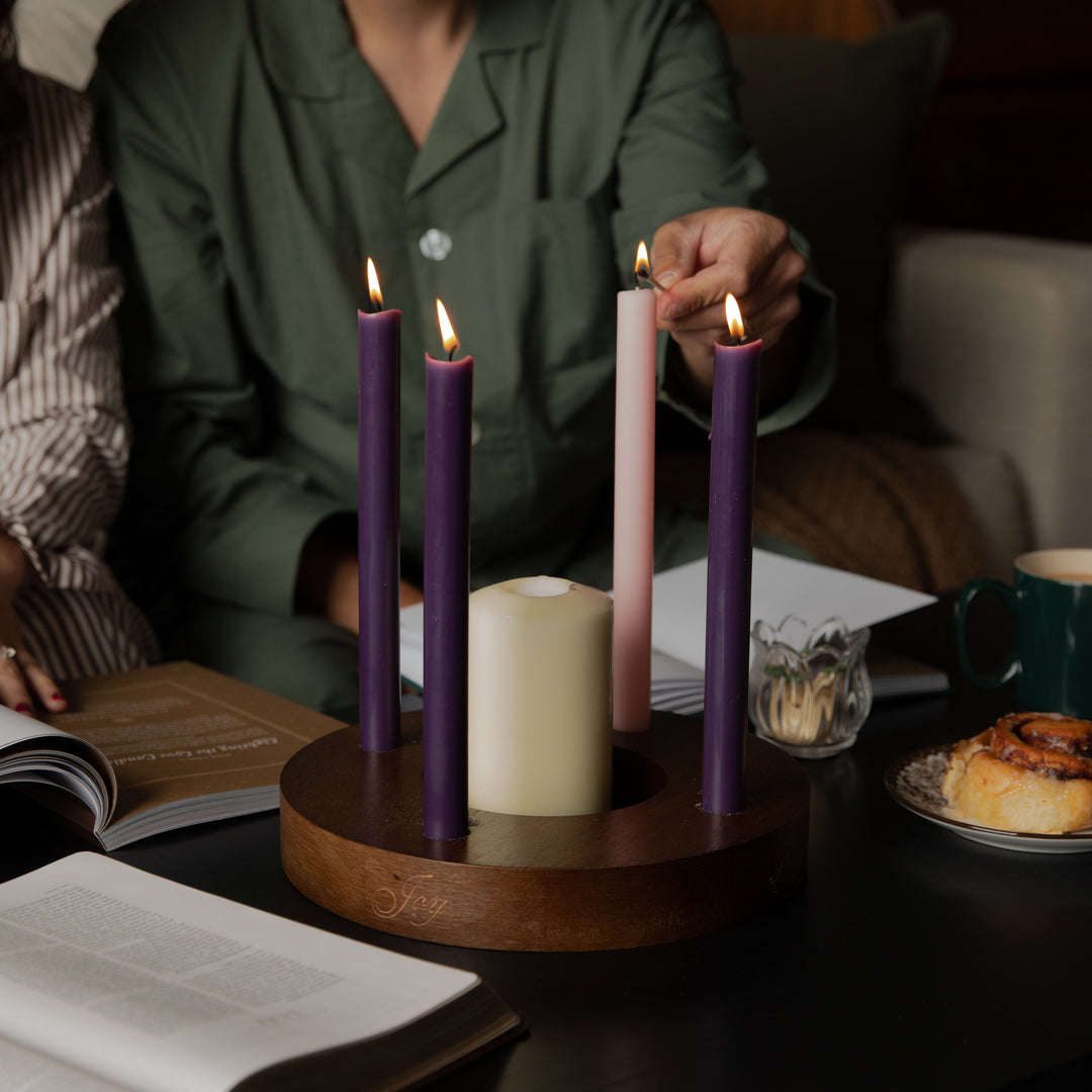 A persons hand lighting a candle on a candle ring