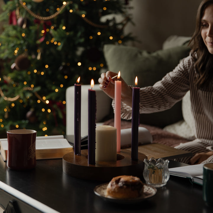 A woman lighting candles on a dark wooden table