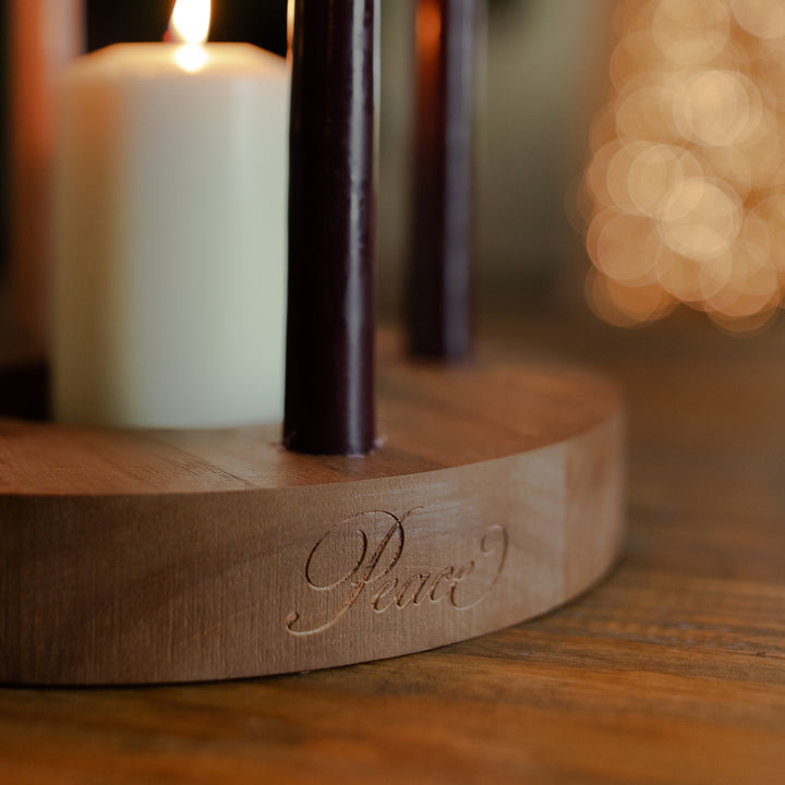 Up close of the word Peace engraved on the side of a wooden candle holder