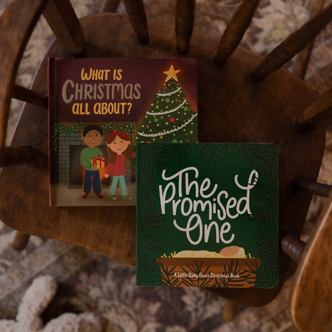 Two children's board books displayed on a wooden chair outdoors. The book on the left is titled 'What Is Christmas All About?' and shows an illustration of children and a Christmas tree.