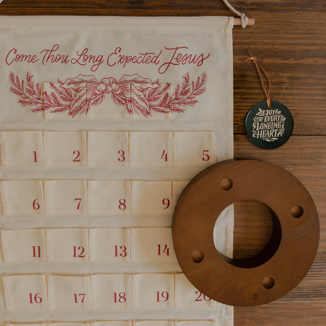 A calendar, a candle ring and a ceramic ornament on a wooden table next to each other