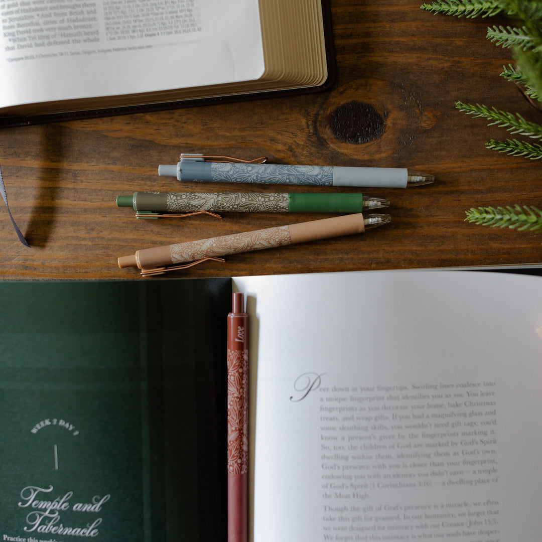 An open advent study with the advent pen set laying on the table above the study with an open bible nearby