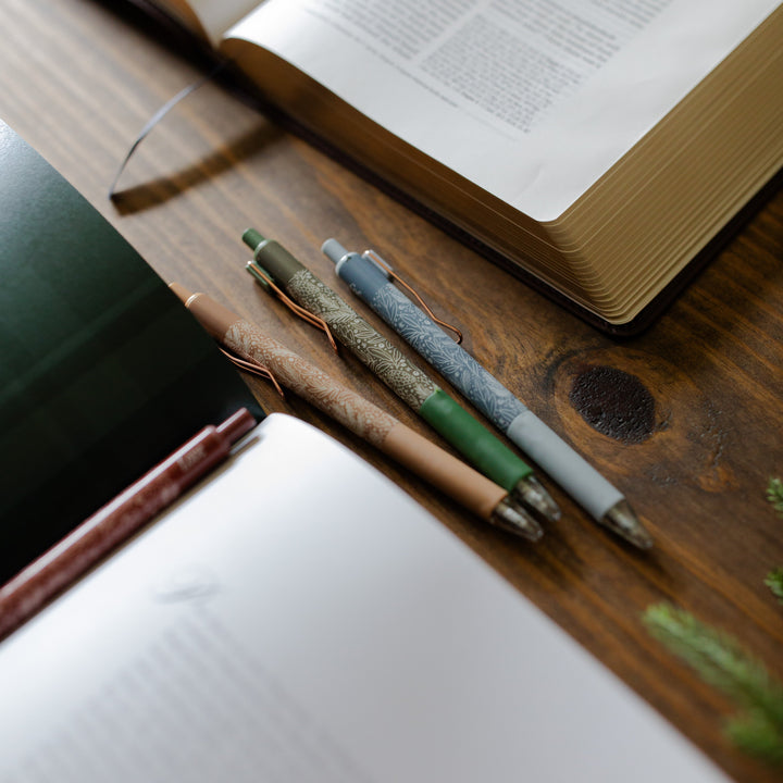 Up close of 3 advent pens from the advent pen set next to an open bible and an open bible study